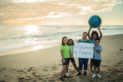 Portrait of mature woman and children with climate change banner at the beach
