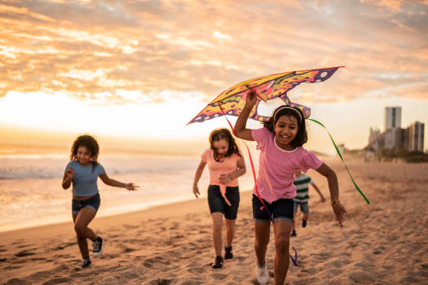 Friends running holding a kite at the beach