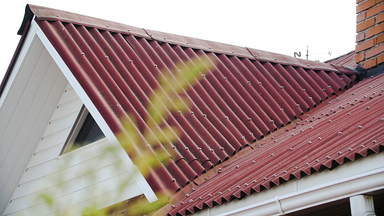 Corrugated roofing roof. Stock footage. Details of red roof made and covered from metal profile. Close-up of roof covering from slopes of side windows.