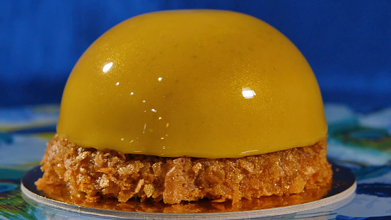 Delicious beautiful cake with yellow frosting. The mirror glaze on a cake round session. Mousse. Yellow.