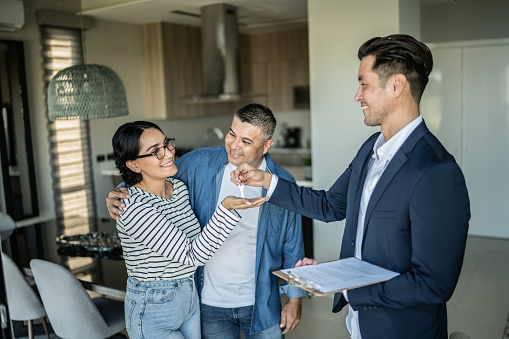 Real estate agent giving  the home keys to a couple at home