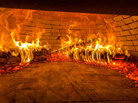 Embers burning with flames in a wood-fired pizza oven