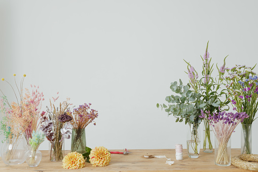 dried flowers in vases on wooden table on white background, flower shop concept