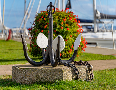 Symbolic photo shipping - displayed old drag anchor in the foreground with blurred sailing yachts in the background