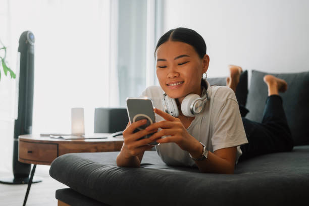 istock Young asian woman using phone at home 1435672842