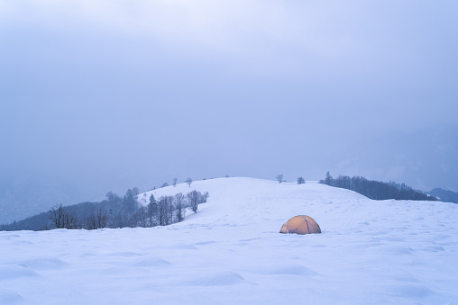 Winter camping with tent in snowy mountains