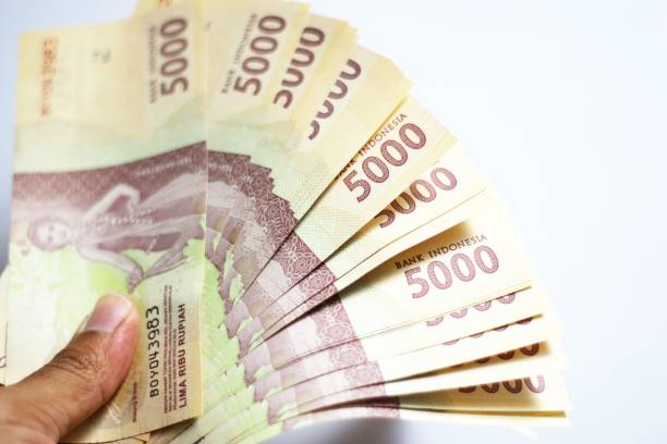 istock People holding Indonesia banknotes of 5000 rupiah. 1435679037