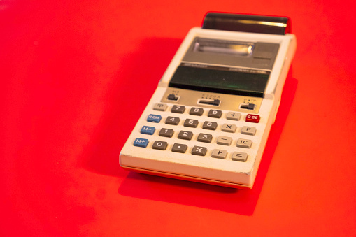 A retro calculator from above on a flat color background.