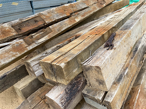 Large wooden rectangular logs or large diameter square cross ties at a construction site.