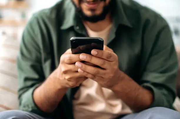 Close-up of a smartphone in a male hands. The concept of online messaging, social media communication, browsing the internet, websites, reading news. Wireless technologies, gadgets