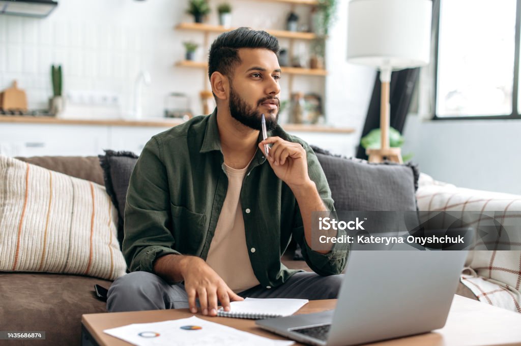 Indien ou arabe intelligent pensif, étudiant ou pigiste, utilisant un ordinateur portable, travaillant ou étudiant à distance, écoutant un webinaire, prenant des notes, des devoirs, s’asseyant à la maison sur un canapé, détournant le regard, réfl - Photo de Contemplation libre de droits Indien ou arabe intelligent pensif, étudiant ou pigiste, utilisant un ordinateur portable, travaillant ou étudiant à distance, écoutant un webinaire, prenant des notes, des devoirs, s’asseyant à la maison sur un canapé, détournant le regard, réfl - Photo de Contemplation libre de droits