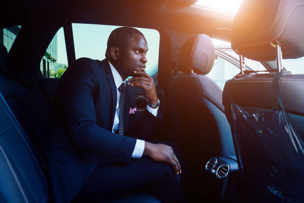 Handsome successful rich african american businessmen in a stylish black business suit and tie sitting in a luxury car. concept of luck and career growth stock photo