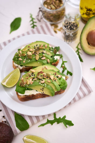 istock Freshly made Avocado and cream cheese toasts on a white ceramic plate and ingredients 1435693982