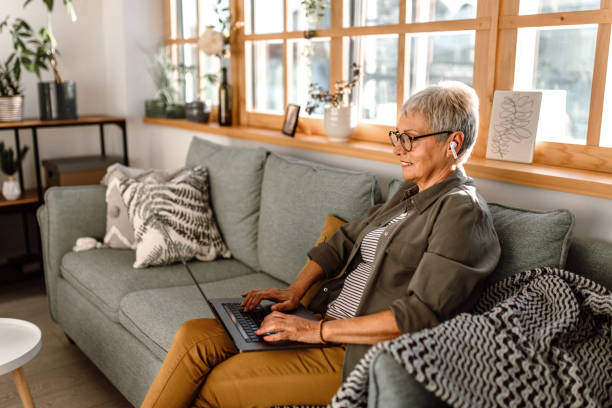 istock Working senior woman using laptop in her sofa 1435698653