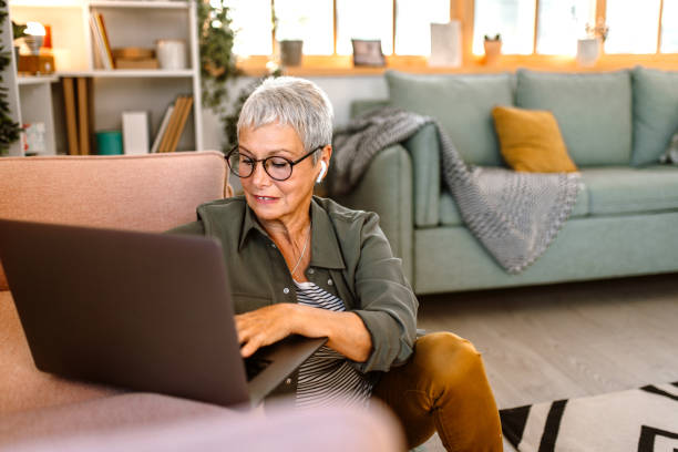 istock Working senior woman using laptop in her sofa 1435698654