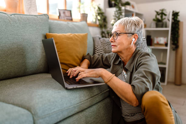 Working senior woman using laptop in her sofa