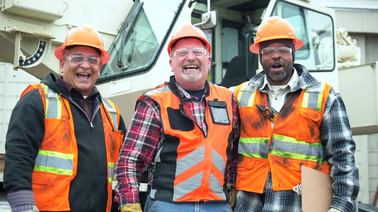 Three multiracial construction workers point at camera