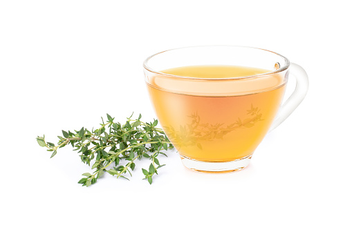 Thyme tea with fresh thyme leaf and dried herbal powder in wooden spoon isolated on white background.