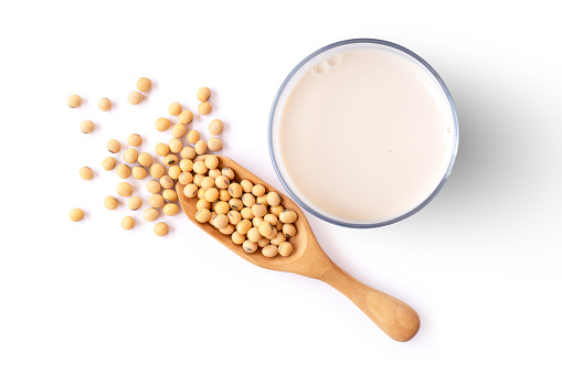 Glass of soy milk with soybean isolated on white background, top view, flat lay.