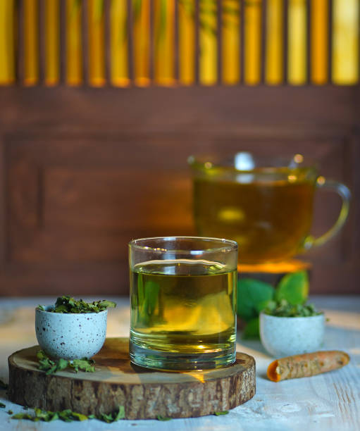 Moringa leaf tea served in glass on the wooden piece of board stock photo