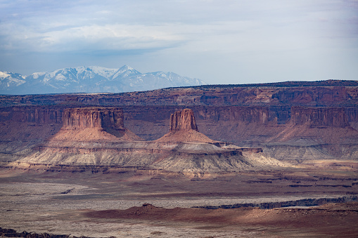 Aerial view overlooking sandstone buttes, plain desert and mountain ranges in Canyonlands National Park, Utah, USA.