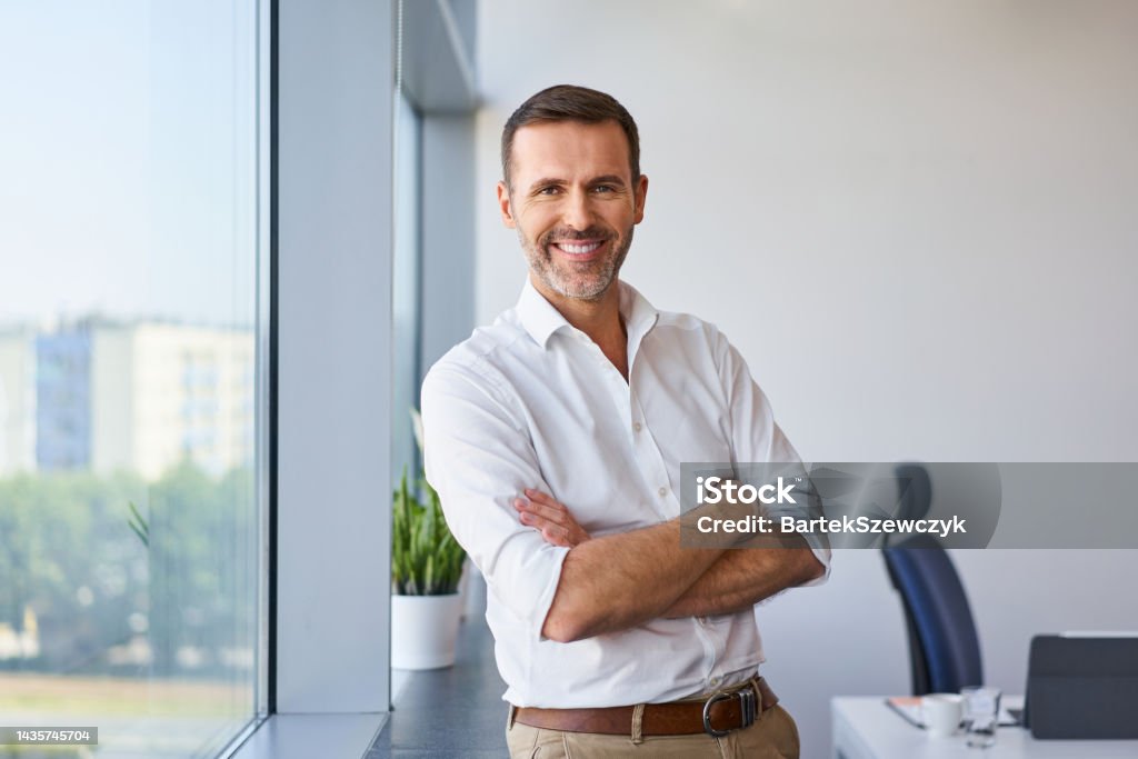 Portrait of smiling mid adult businessman standing at corporate office Men Stock Photo