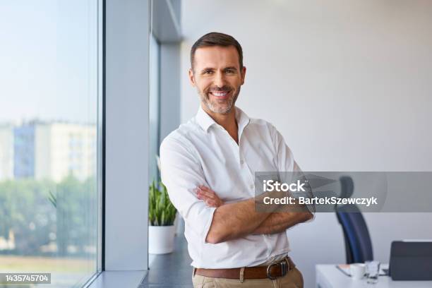 Portrait Of Smiling Mid Adult Businessman Standing At Corporate Office Stock Photo - Download Image Now