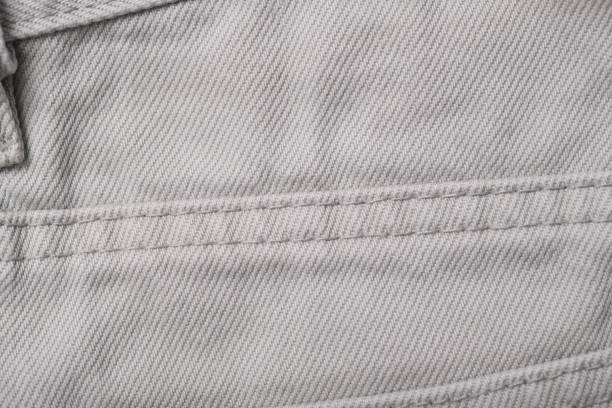 Old background from beige jeans texture close up. Denim stitch.