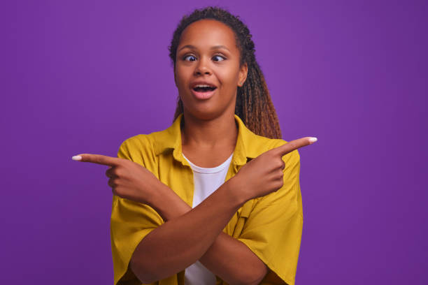 istock Young funny African American woman shows with hands different sides in studio 1435758448