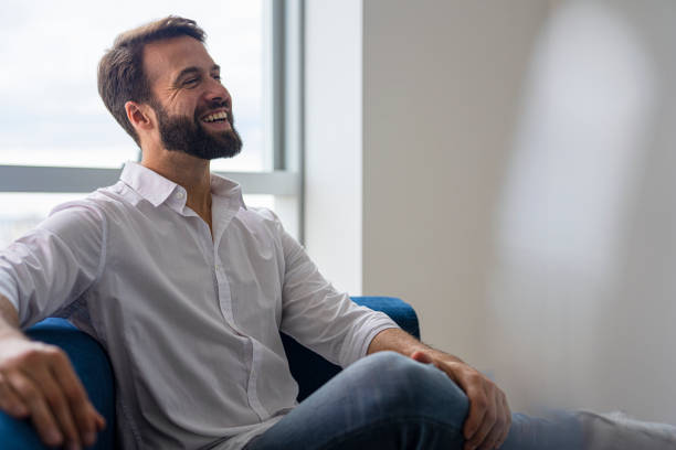 Happy young entrepreneur sitting on sofa discussing business with partners