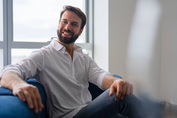 istock Smiling young male manager sitting on couch while waiting for meeting to begin 1435761852