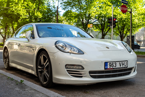 Tallinn, Estonia - June 05 2022: White shiny Porsche Panamera parked on the city street on a sunny summer evening.