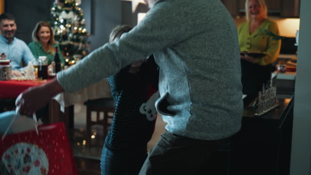 Granddaughter runs to hug grandfather who is visiting family on a Christmas