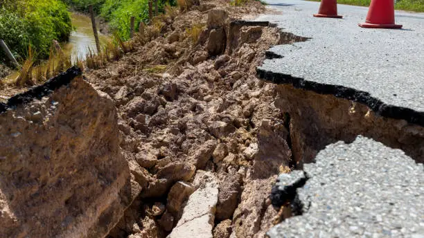 Landslide caused by rains occurs broken road asphalt. Broken asphalt road collapsed and fallen.  Road collapses. Cracked asphalt road. Construction site.