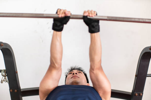 Man doing lunges with barbell overhead during workout in gym gym