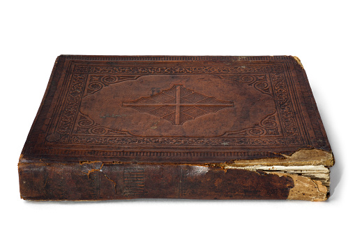Antique bible with leather-bound cover on a white background.