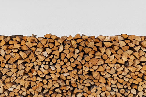 Image of a stack of firewood by a wooden wall