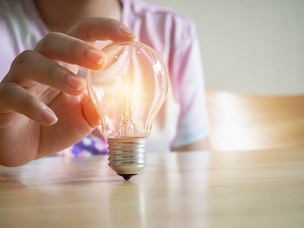 istock Young women hand holding light bulb on the wood table. 1435781340