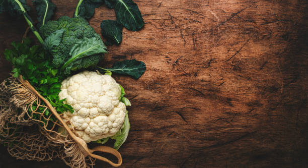 istock Autumn food background with cauliflower and broccoli in string bag on old rustic wood kitchen table, top view, copy space banner 1435782029