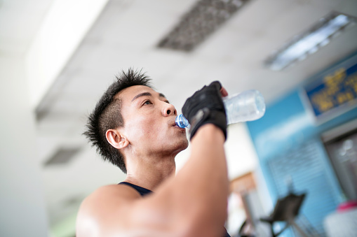 Man drinking from water bottle in gym