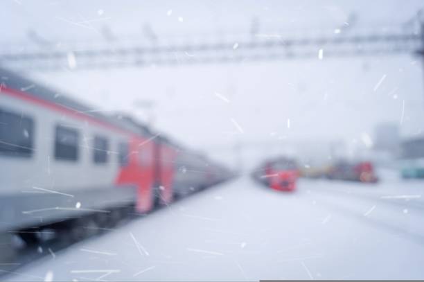 Blurred passenger electric train at a suburban train station. Blurry background image of a train and station in winter. Winter background