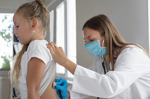 Female doctor listen to child back at checkup