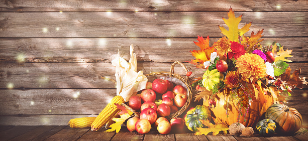 Happy Thanksgiving. Thanksgiving decoration with pumpkins, bouquet of flowers, fruits and falling leaves on rustic wooden table