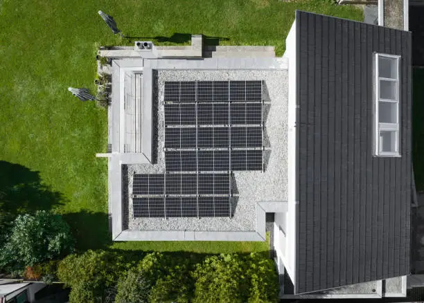 New Solar Panels - Photovoltaic System installed on top of flat roof on modern Private Home Green Building. Drone Satellite Point of View. Green Energy - Sustainable Energy at Home Concept. Southern Germany, Europe