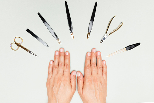Directly above view of female hands with manicure utilities on white background.