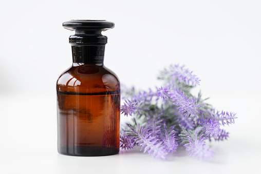Front view of beauty serum bottle and lavender flowers on pure white background.