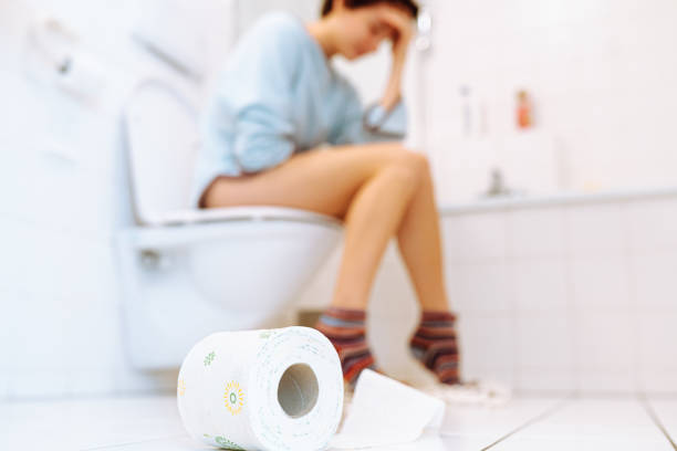 concept of constipation, diarrhea, abdominal pain or cramps. copy space silhouette of woman sitting on toilet on blurred background. Sick, unhealthy woman, teenager, suffering from diarrhea, constipation and cystitis in toilet. Abdominal pain during PMS. healthcare and pain concept constipation stock pictures, royalty-free photos & images