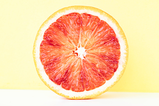 Single blood orange slice on yellow background.