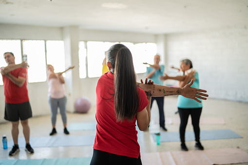 Yoga instructor stretching with students at the studio