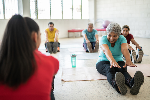 Yoga instructor stretching with senior people at the studio